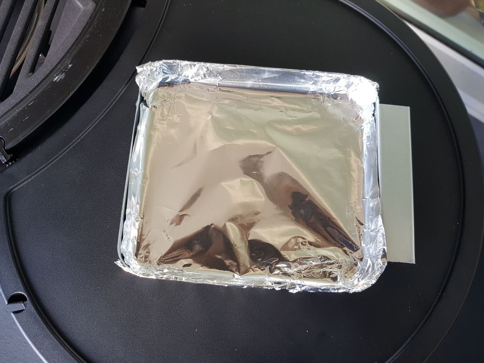 Foil-wrapped food on a black grill surface