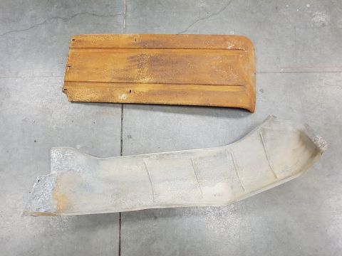 1978 Ford Bronco - Two weathered vehicle parts, a rusty tailgate and a metal shield, lie on a concrete surface.