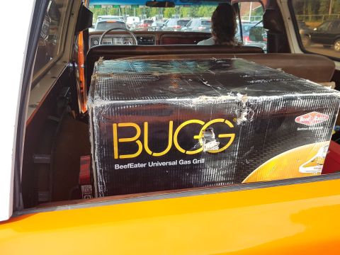 1978 Ford Bronco - The interior of an orange vehicle is visible, with a large box for a BeefEater Universal Gas Grill taking up most of the cargo space.