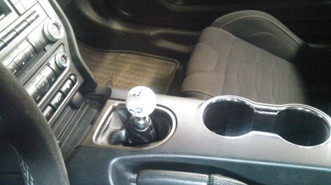 2017 Ford Mustang - The interior of a car features a manual shifter with a custom shift knob and dual cup holders.