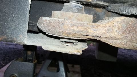 Rusty suspension part on jack stands, showing metal fatigue and wear
