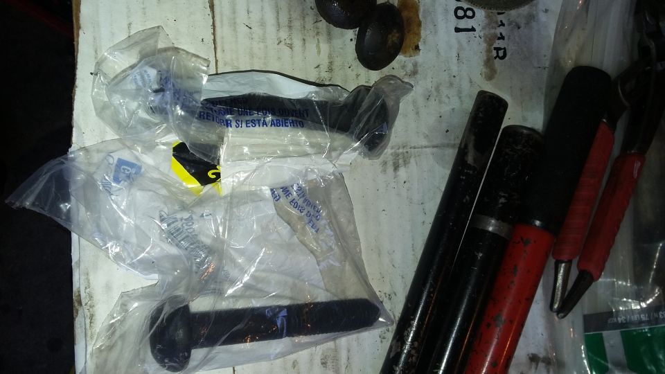 Several new automotive parts in plastic packaging next to various tools on a workbench