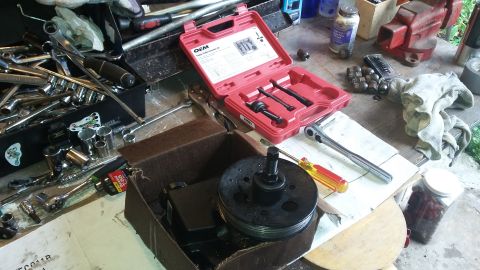 Pulley and power steering pump in a box with a tool kit and assorted wrenches on a workbench