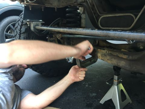 1996 Ford Bronco - Mechanic works on the suspension of a 1996 Ford Bronco, with the Supermotors.net logo visible at the bottom right.