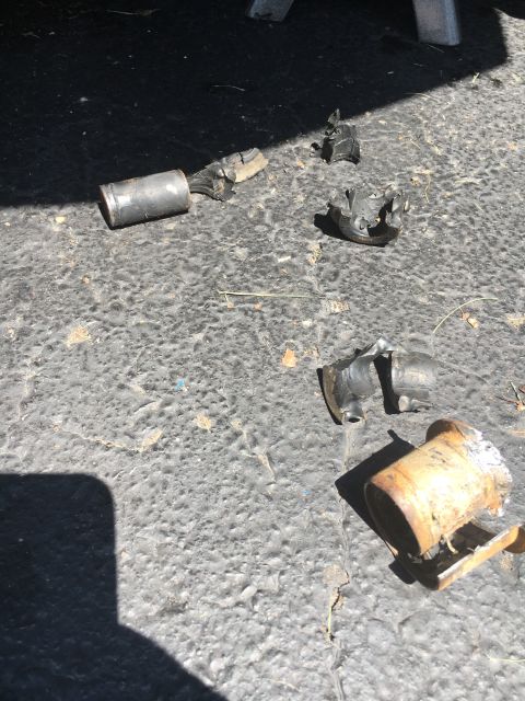 1996 Ford Bronco - Several pieces of a broken exhaust pipe lie on a textured surface, with a watermark for SuperMotors.net visible.