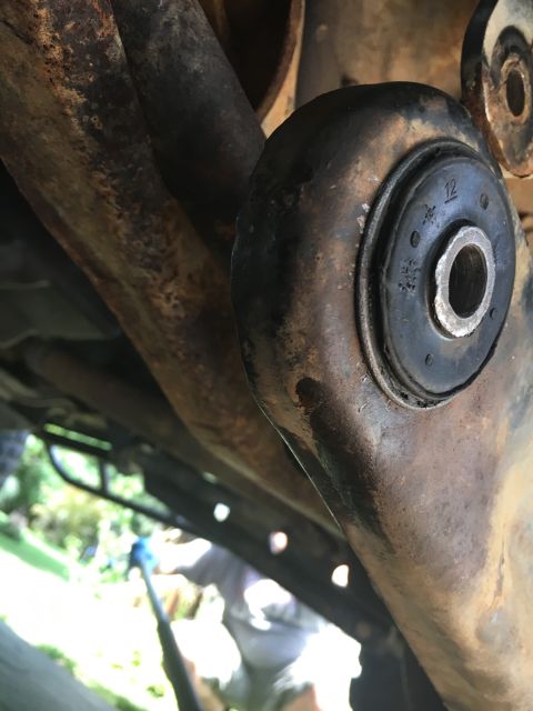 1996 Ford Bronco - Undercarriage view of heavily rusted vehicle suspension components, including a rubber bushing.