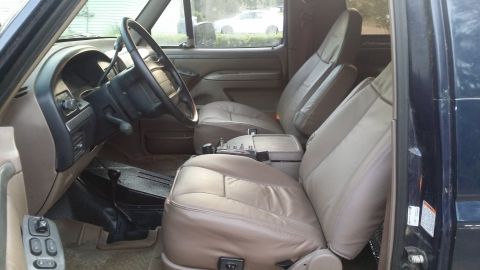 1995 Ford Bronco - The interior of a truck shows tan leather seats and the dashboard area.