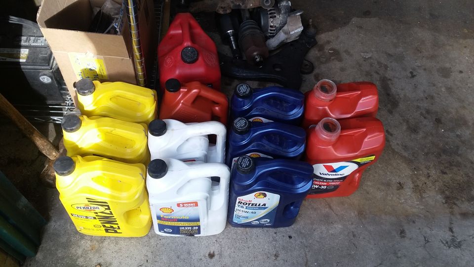 Stack of yellow, white, and blue oil containers with red gas cans