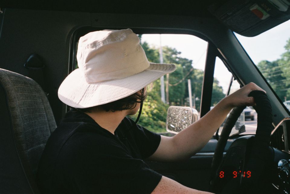 Person wearing a wide-brimmed hat driving, view from passenger side