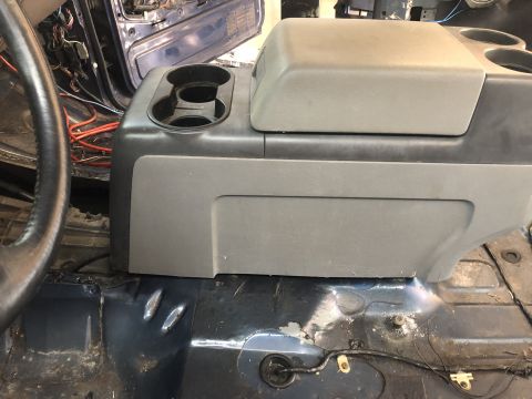 1995 Ford Bronco - The interior of a 1995 Ford Bronco shows a gray center console with cup holders and a storage compartment.