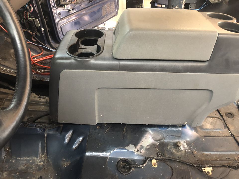 Gray center console with dual cup holders and storage compartment in a 1995 Ford Bronco