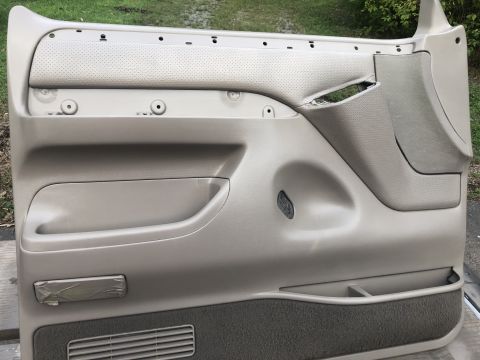 1995 Ford Bronco - This is a close-up of a vehicle's interior door panel, showing its various components and some wear.