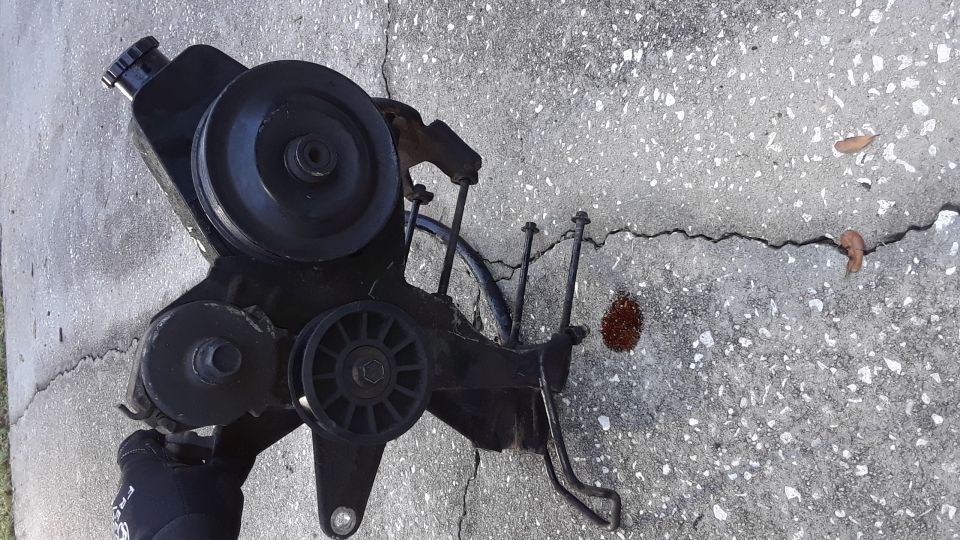 Power steering pump assembly with pulleys on a cracked concrete surface