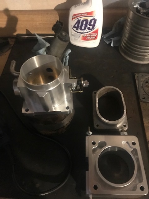 2000 Ford Explorer - Aftermarket throttle body and adapter plates are laid out on a workbench, alongside a bottle of 409 cleaner.