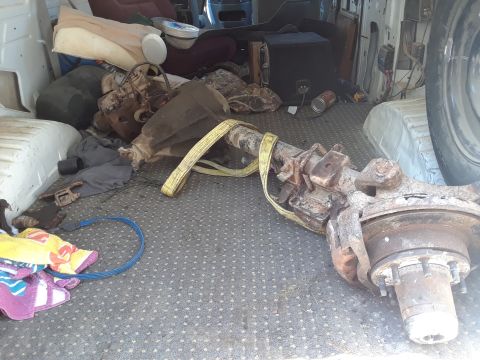 1994 Ford Bronco - Various parts, including an axle assembly, are stored inside a vehicle's cargo area.