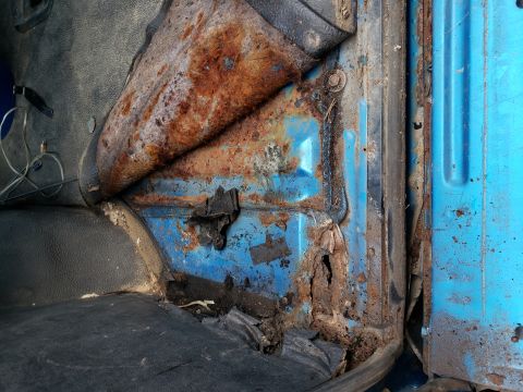1995 Ford Bronco - Severe rust damage is visible on the interior door frame and floor of this vehicle.