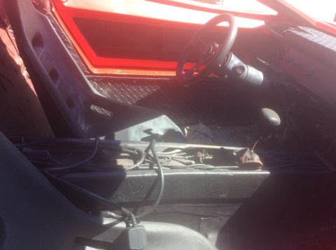 1992 Ford Bronco - The interior of a red vehicle features racing seats and a steering wheel, with visible wiring and components in the center console.