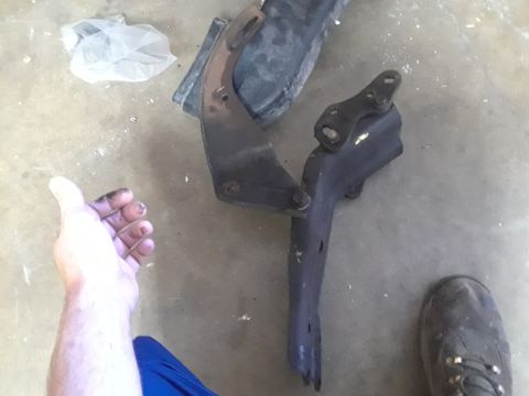 1994 Ford Bronco - Metal bracket parts are shown on a concrete floor, next to a hand and a boot.