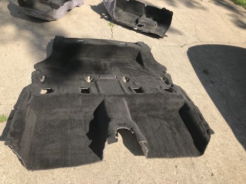 2015 Ford Explorer - Car carpet and trim pieces removed from a vehicle and laid out on concrete for cleaning or replacement.