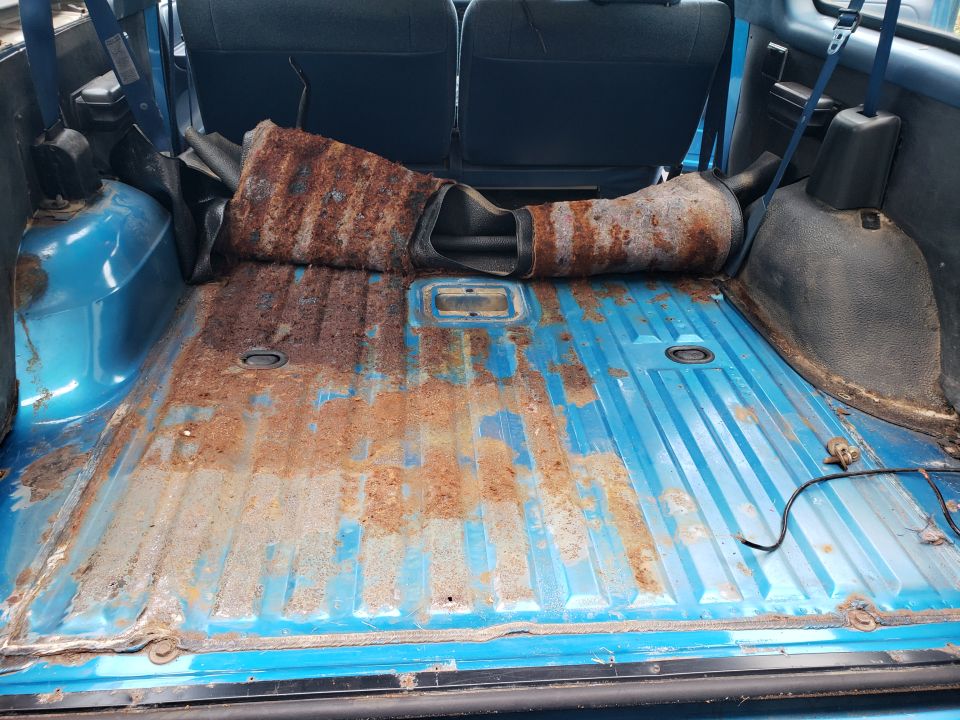 blue vehicle cargo area with rusty floor and a removed exhaust pipe