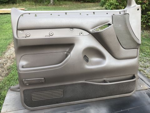 1995 Ford Bronco - A detached tan car door panel is shown, revealing its interior components and storage features.
