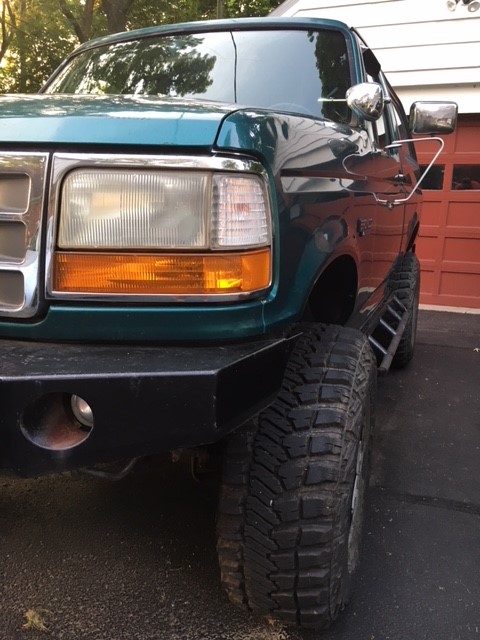 1996 Ford Bronco - 1996 Ford Bronco with custom front bumper and off-road tires parked in front of a garage.