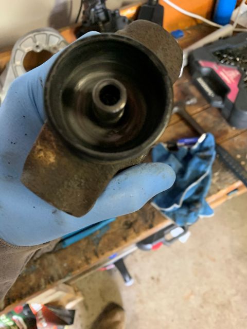 1996 Ford Bronco - A gloved hand holds a rusty automotive part against a workbench background.