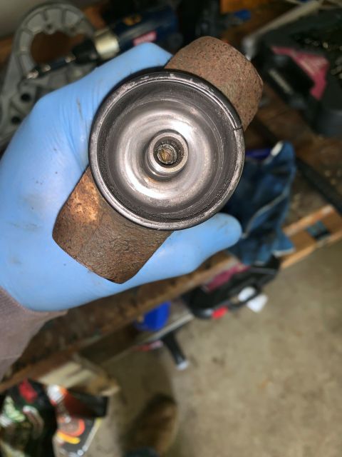 1996 Ford Bronco - A gloved hand holds a rusted metal part, possibly from a vehicle's exhaust system or suspension.