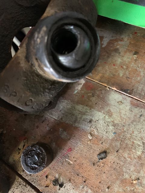 1996 Ford Bronco - A close-up view of a vehicle's brake caliper part, resting on a wooden workbench.