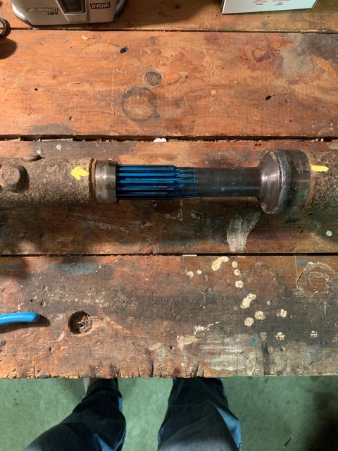 1996 Ford Bronco - A driveshaft component with blue splined end is shown on a workbench.