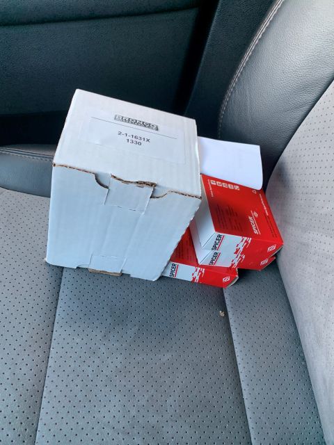 1996 Ford Bronco - Boxes of auto parts are placed on the perforated gray seats of a vehicle.