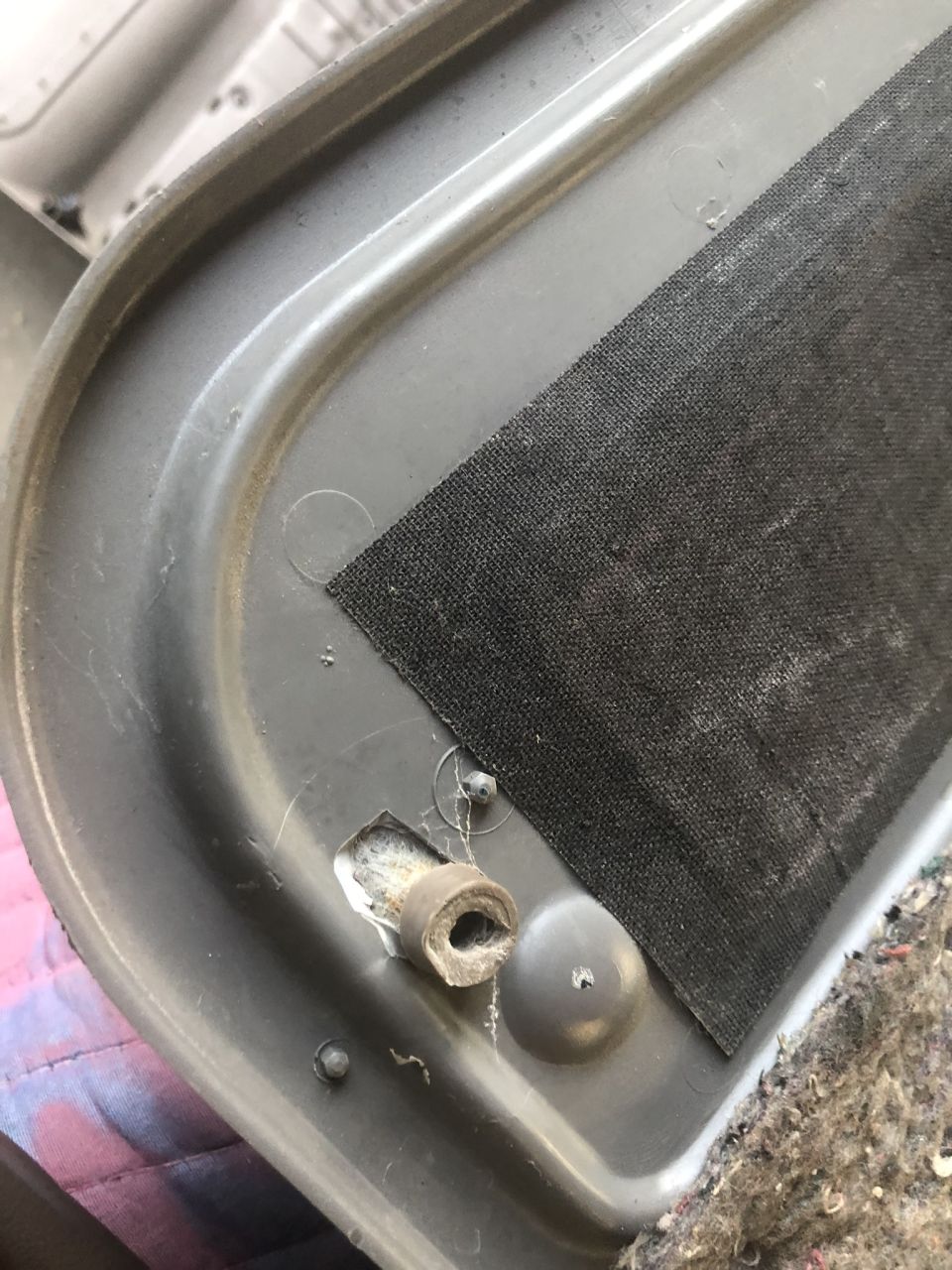 Close-up of gray interior door panel trim with black fabric and a damaged clip
