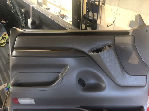 1995 Ford Bronco - Close-up of a vehicle's interior door panel, showing the armrest and textured material.