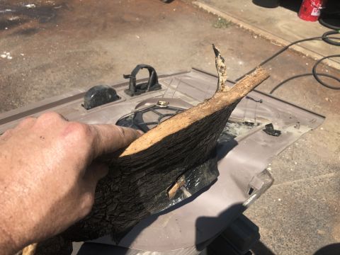 1995 Ford Bronco - A piece of bark is being held over a disassembled car door panel, revealing interior components.