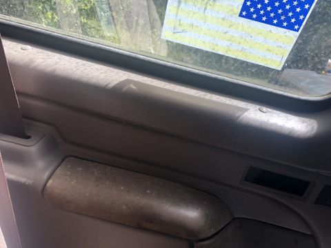 1995 Ford Bronco - Close-up of a vehicle's interior door panel, with an American flag sticker visible through the window.