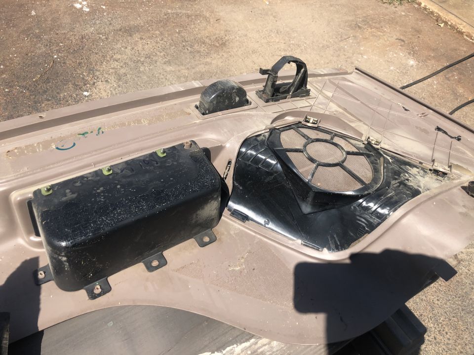Car interior door panel removed, showing speaker grille and black housing unit