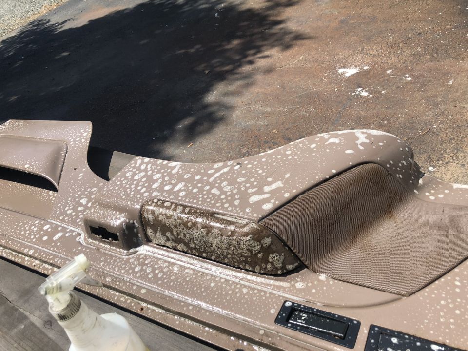 Brown interior panel covered in soap suds, with a spray bottle nearby