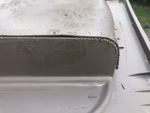 1995 Ford Bronco - Detail of a painted panel, possibly from a vehicle interior, showing rivets and signs of wear.