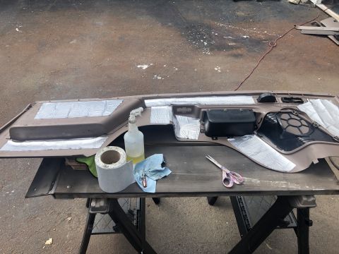 1995 Ford Bronco - A vehicle dashboard panel is being worked on, with sound-dampening material and tools laid out.