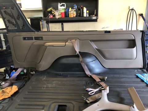 1995 Ford Bronco - Interior panel and seatbelt removed from vehicle, showing the cargo area floor.