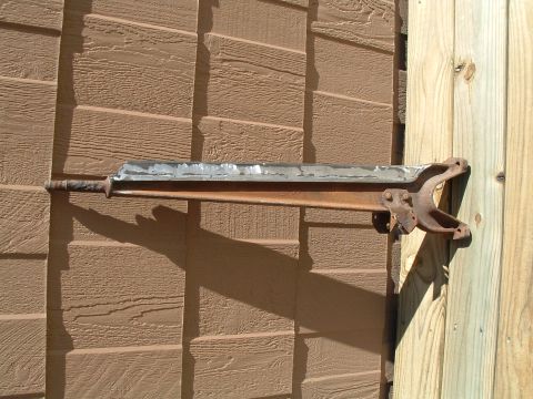 1979 Ford Bronco - A rusted metal component is attached to a wooden wall, casting a long shadow.