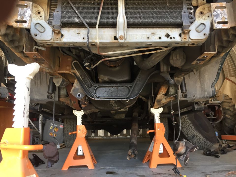Underside of a truck on jack stands, showing the drivetrain and suspension components