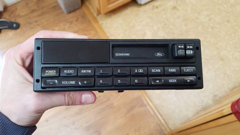 1994 Ford Bronco - A Ford car stereo is held in a hand, showing its various control buttons and a Dolby System indicator.