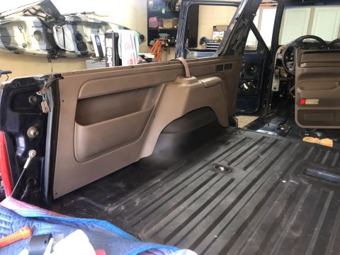 1995 Ford Bronco - Interior of a 1995 Ford Bronco undergoing restoration, showing removed door panel and bare cargo floor.