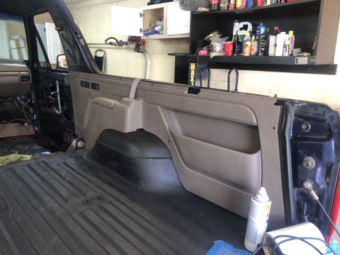 1995 Ford Bronco - The interior of a vehicle is shown with the door panel removed, revealing the cargo area and exposed wiring.