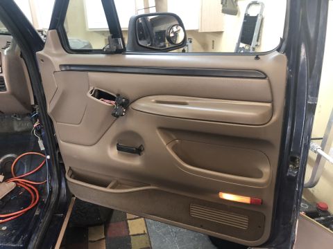 1995 Ford Bronco - Interior door panel of a 1995 Ford Bronco showing the tan trim and exposed wiring.