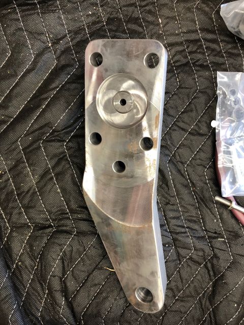 1992 Jeep Wrangler - A metal bracket with various bolt holes and a central circular recess is shown against a quilted black background.