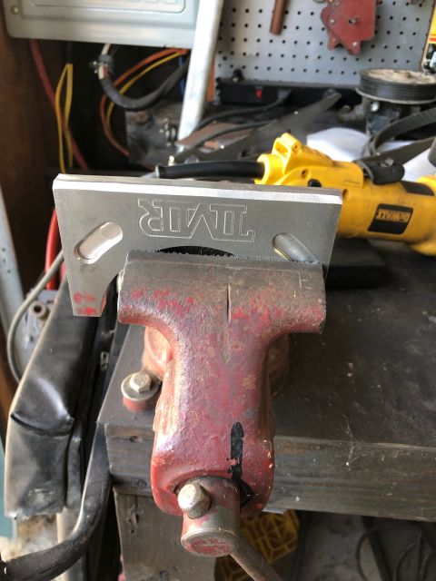 1992 Jeep Wrangler - A metal component is secured in a vise, with a power tool visible behind it.