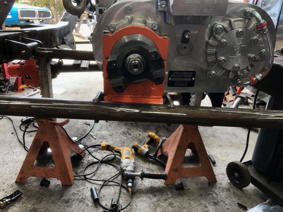 Transfer case mounted on orange bracket, supported by jack stands