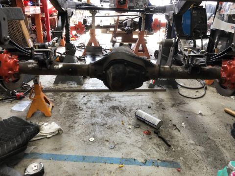 1992 Jeep Wrangler - The rear axle assembly of a vehicle is supported by jack stands in a workshop environment.